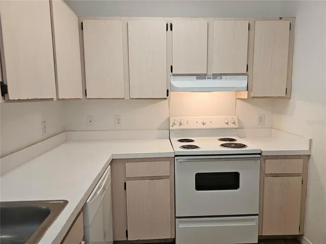 a kitchen with granite countertop cabinets stainless steel appliances a sink and a window