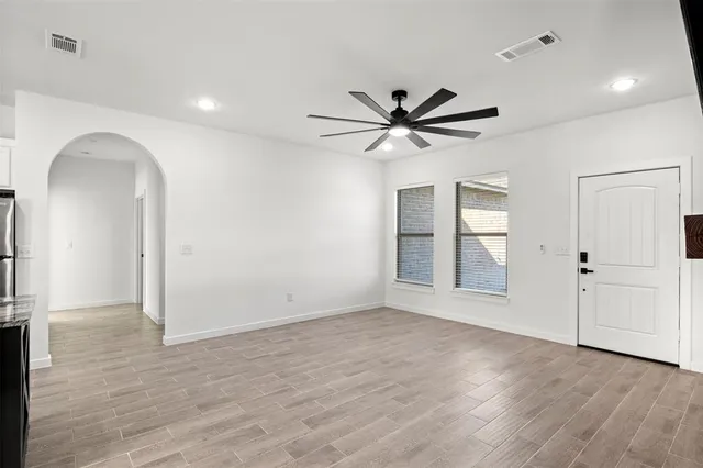 an empty room with wooden floor cabinet and windows