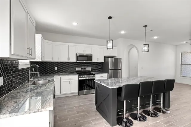 a kitchen with kitchen island granite countertop a sink a counter space appliances and cabinets