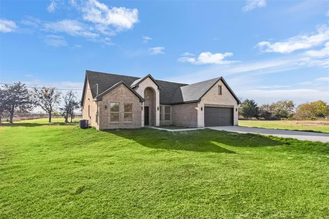 a view of a house next to a big yard and large trees