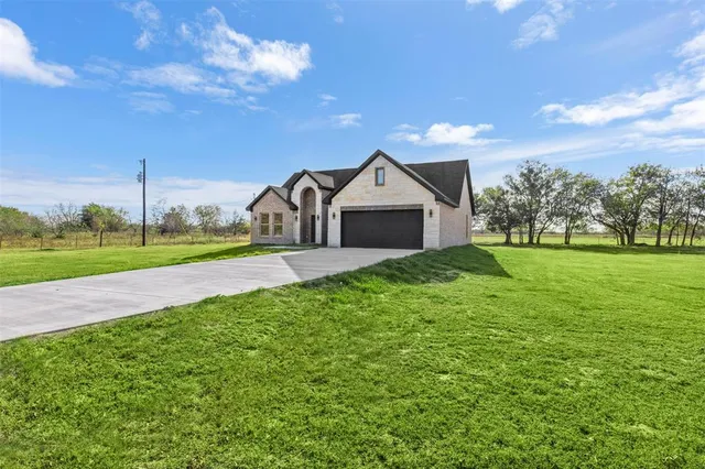 a view of a house with a big yard and large tree