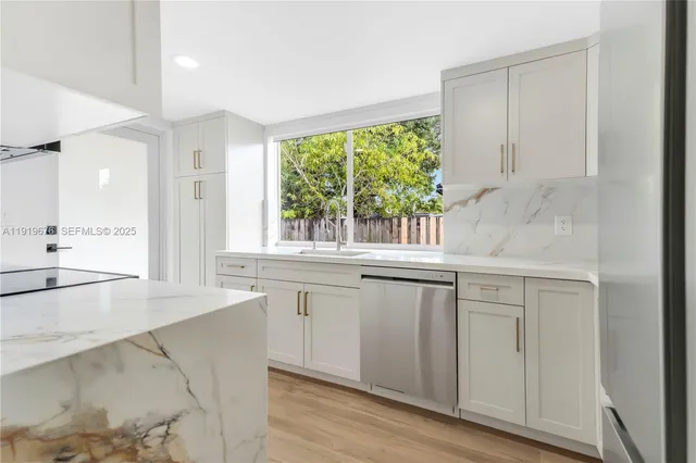 a kitchen with stainless steel appliances white cabinets a sink and a stove