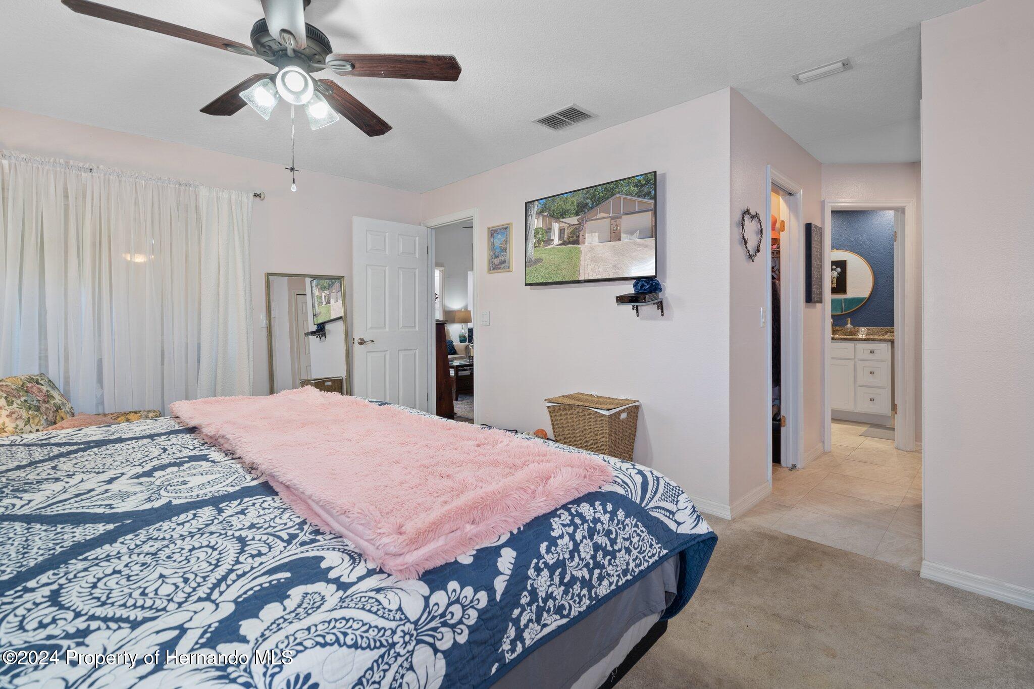 7427 Heather Walk Drive Spring Hill, FL 34613 - Photo 26 of 36 a bedroom with a bed and a chandelier