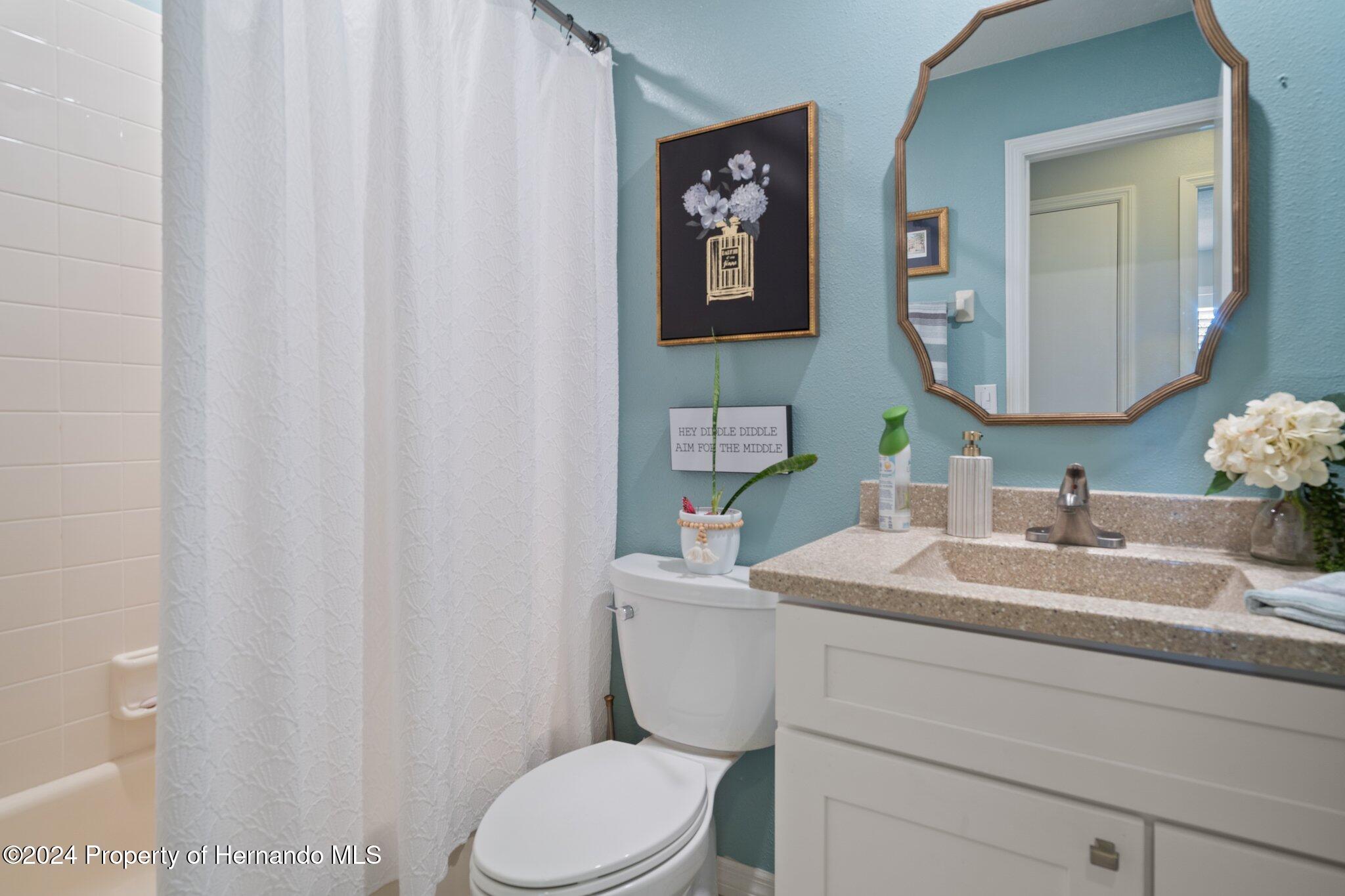 7427 Heather Walk Drive Spring Hill, FL 34613 - Photo 33 of 36 a bathroom with a granite countertop sink mirror vanity and toilet