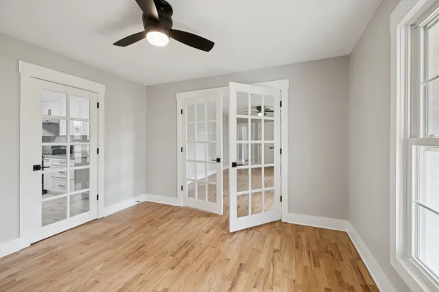 a view of a room with wooden floor a ceiling fan and windows