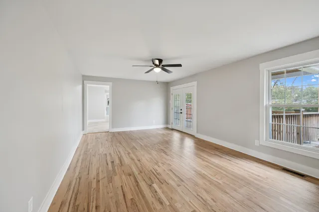 a view of an empty room with a window and wooden floor