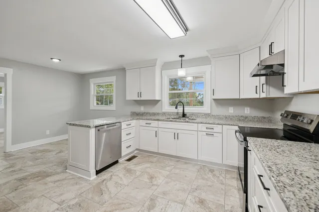 a kitchen with granite countertop stainless steel appliances a sink stove and cabinets