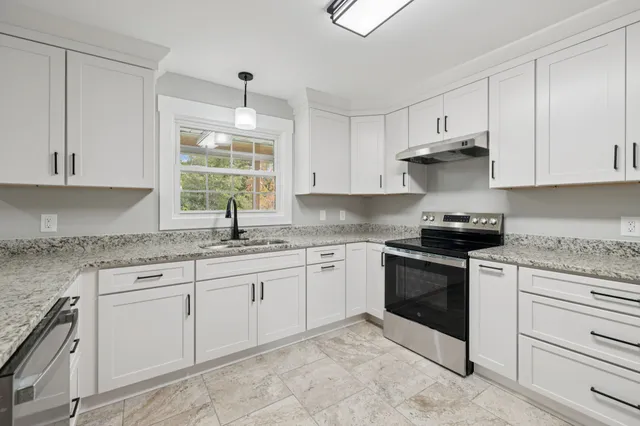 a kitchen with granite countertop white cabinets white appliances with a sink and dishwasher