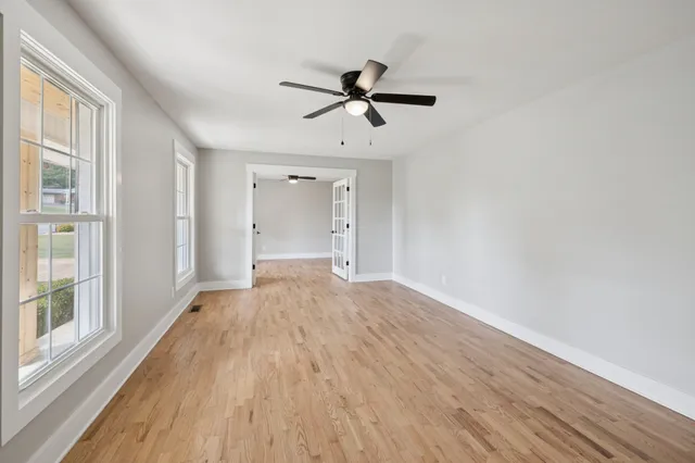 an empty room with wooden floor and windows