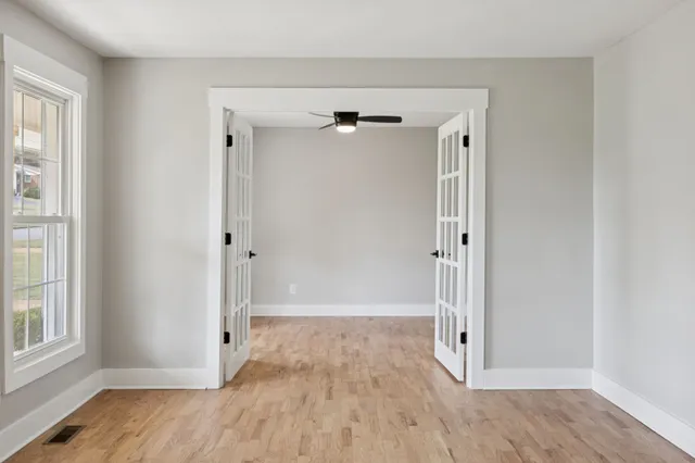 a view of an empty room with a window and a ceiling fan