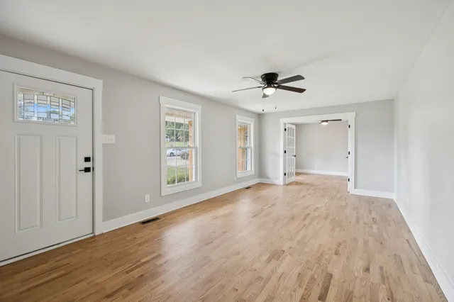 a view of empty room with wooden floor and fan