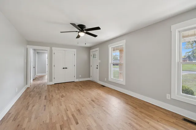 an empty room with wooden floor cabinet and windows