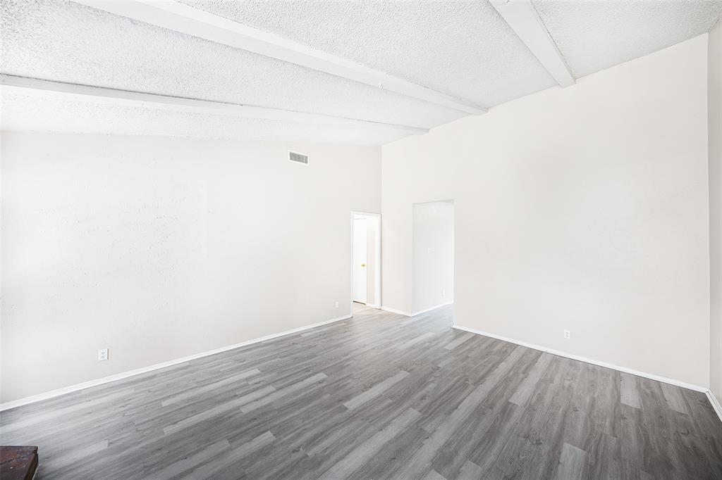 1111 West Rundberg Lane Austin, TX 78758 - Photo 2 of 6 This room features vaulted ceilings with exposed beams, light-toned walls, and grey wood-look flooring