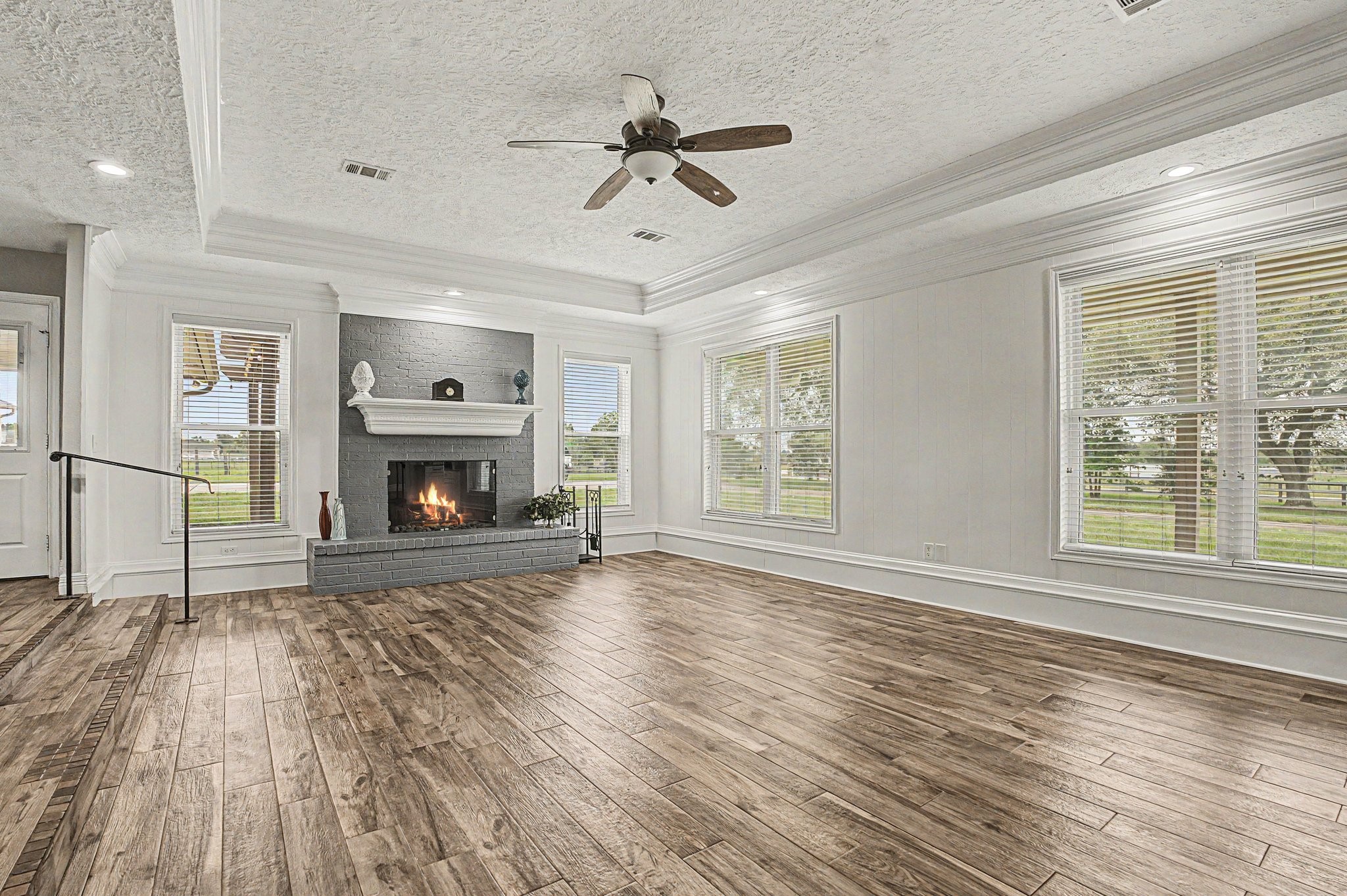 35564 Brumlow Road Hempstead, TX 77445 - Photo 6 of 46 an empty room with windows a fireplace a ceiling fan and wooden floor