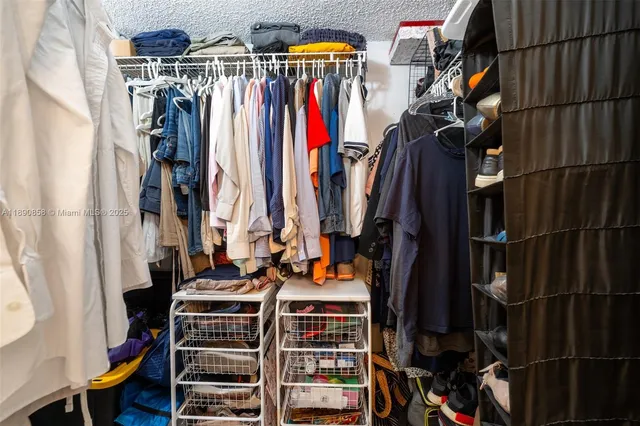 a view of walk in closet with clothes and shoes