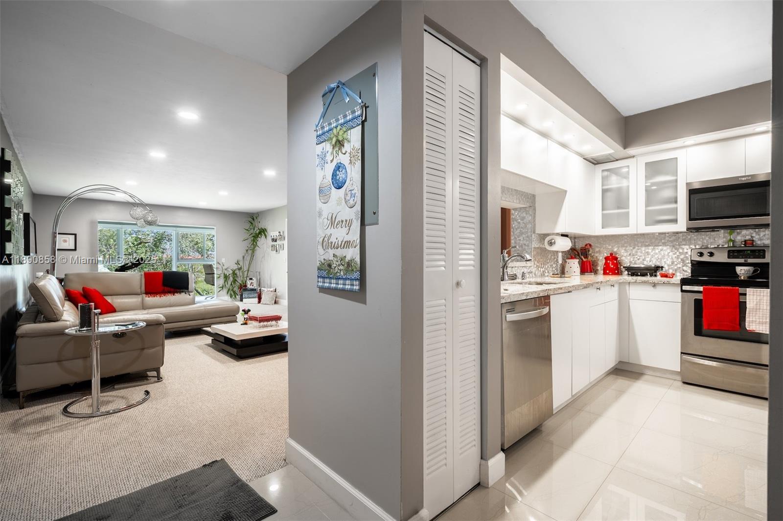 1201 Southwest 128th Terrace, Unit 407E Pembroke Pines, FL 33027 - Photo 7 of 26 a kitchen filled with furniture a flat screen tv and a refrigerator