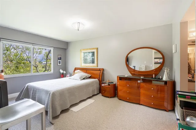 a bedroom with a bed a mirror on desk and chair