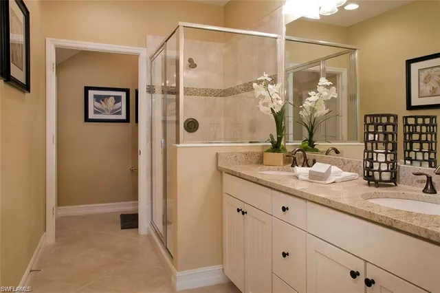 a bathroom with a granite countertop sink a mirror and shower