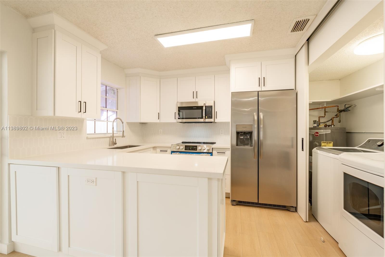 The Hammocks Miami, FL 33196 - Photo 16 of 38 a kitchen with stainless steel appliances granite countertop a refrigerator a stove a sink and white cabinets with wooden floor