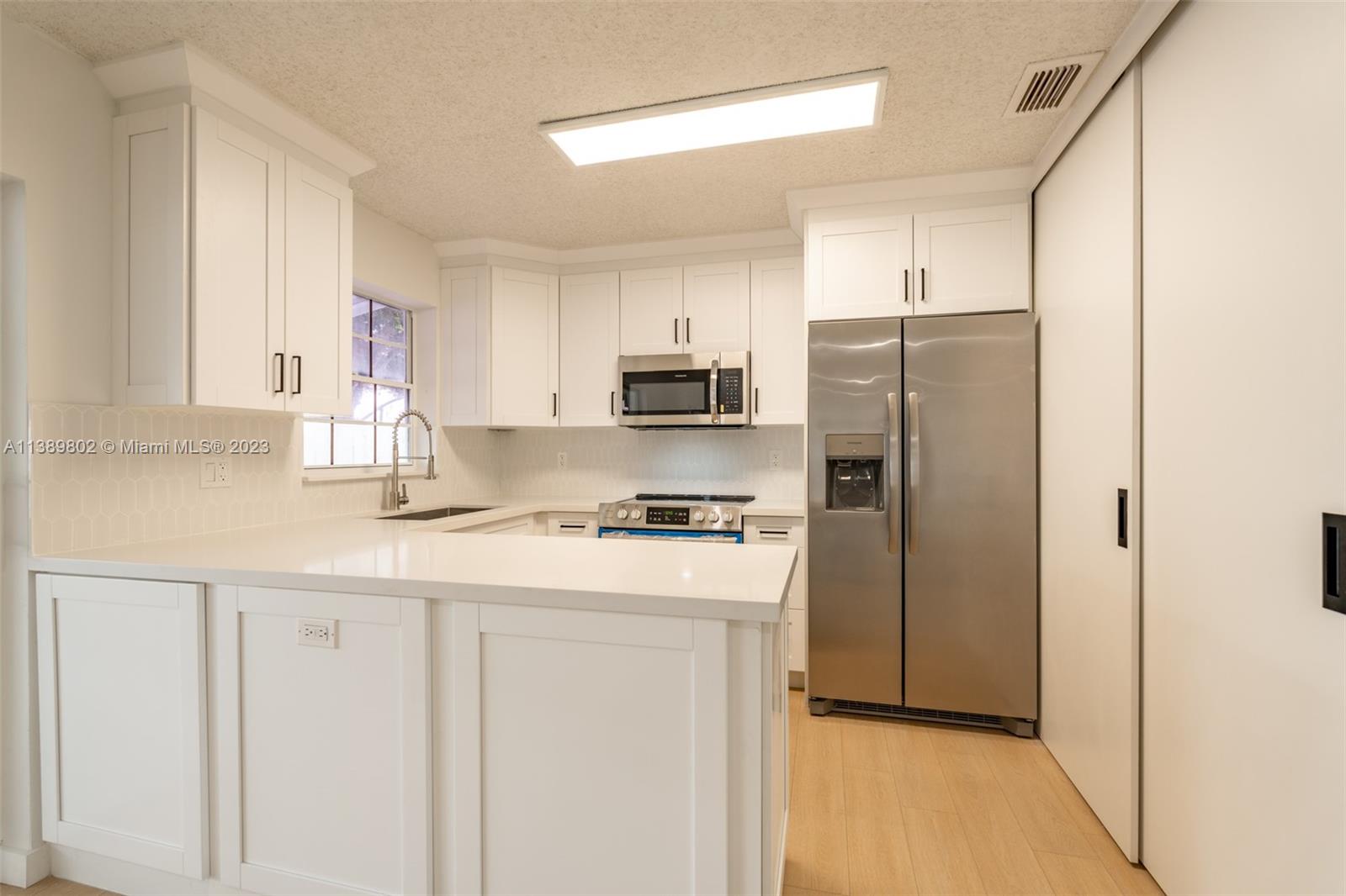 The Hammocks Miami, FL 33196 - Photo 17 of 38 a kitchen with stainless steel appliances granite countertop a refrigerator a stove a sink and white cabinets with wooden floor