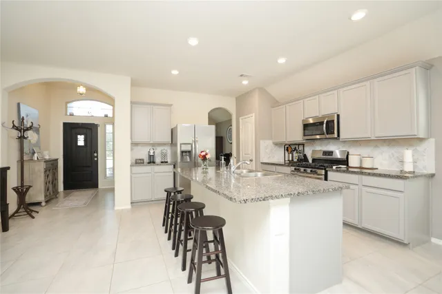 a kitchen with stainless steel appliances granite countertop a refrigerator and a stove top oven