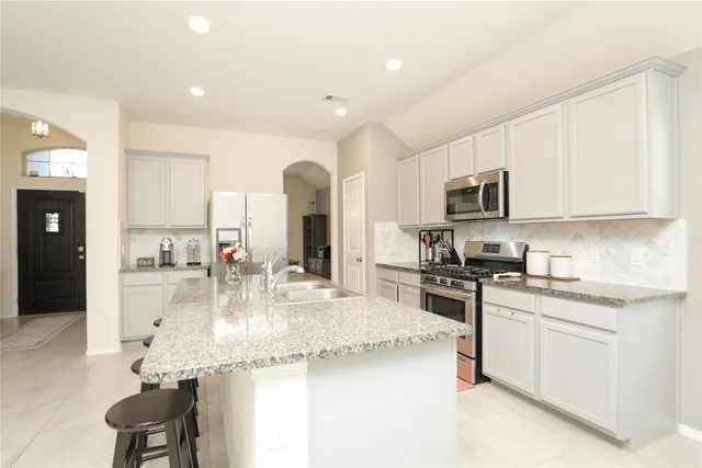 a kitchen with kitchen island granite countertop stainless steel appliances a sink a stove and cabinets