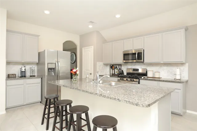 a kitchen with granite countertop a sink stainless steel appliances and white cabinets