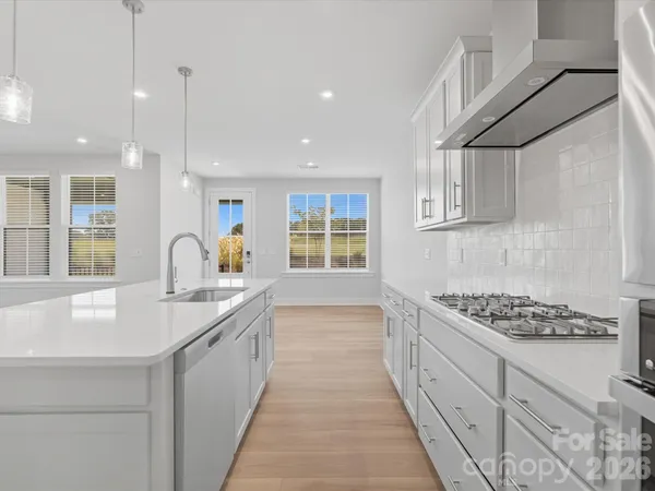 a large kitchen with stainless steel appliances kitchen island a large counter top and a wooden floors