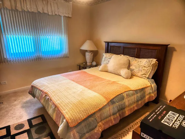 a bedroom with a bed and a lamp on dresser