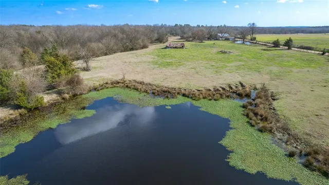 an aerial view of a houses with outdoor space and trees all around