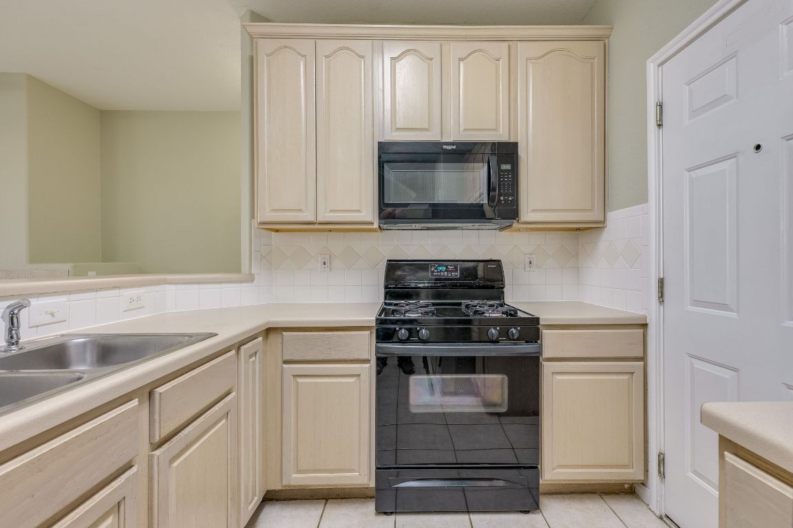 2100 Pipers Field Drive, Unit 14 Austin, TX 78758 - Photo 13 of 30 a kitchen with white cabinets and black appliances