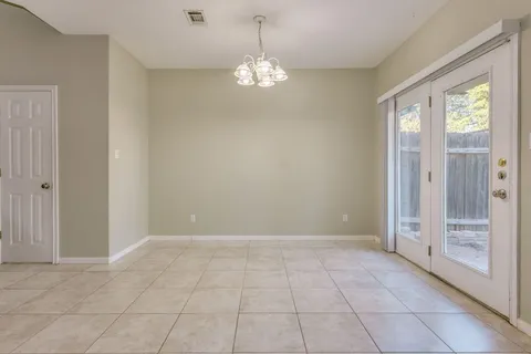 a view of an empty room with window and chandelier