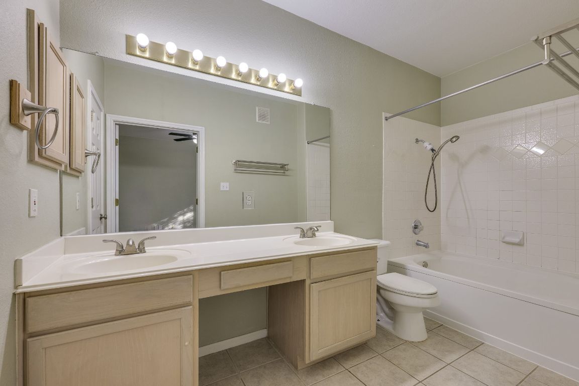 2100 Pipers Field Drive, Unit 14 Austin, TX 78758 - Photo 21 of 30 a bathroom with a double vanity sink toilet mirror and shower