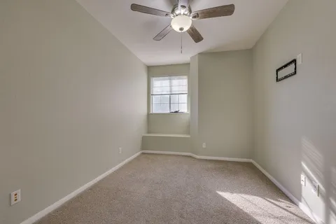an empty room with a window and a fan
