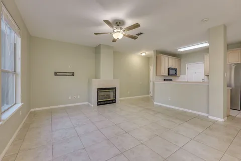 a view of an empty room with a ceiling fan and window