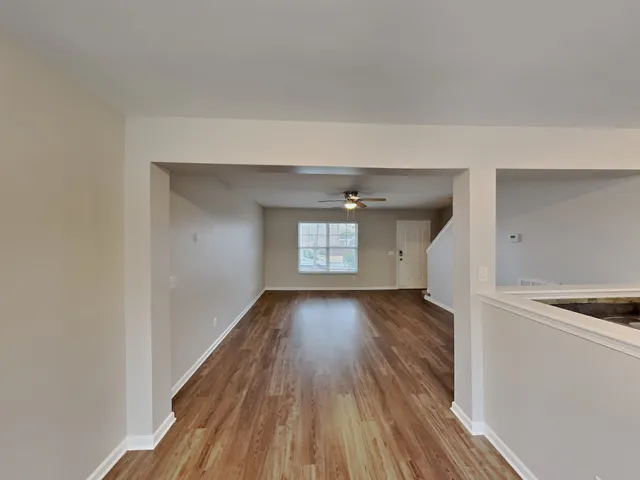 a view of a hallway with wooden floor and a refrigerator