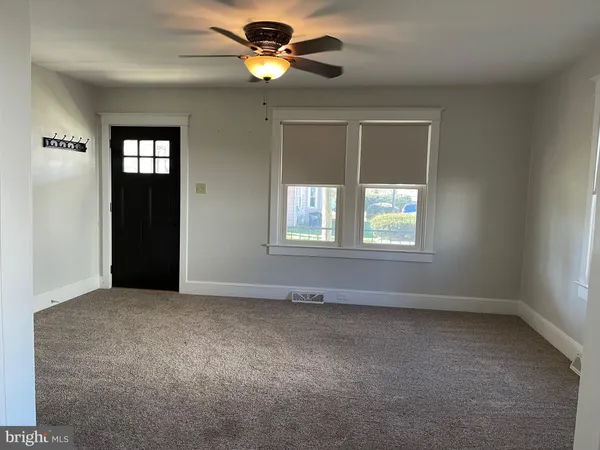 an empty room with windows and fan