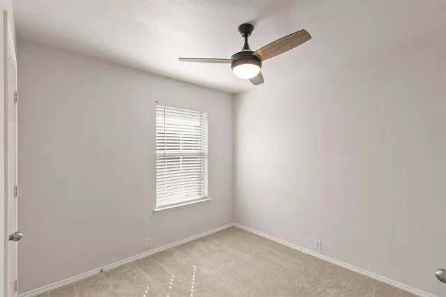 an empty room with a window and a fan