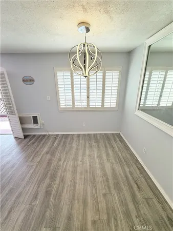 an empty room with wooden floor exposed radiator and windows