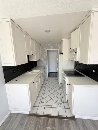 a kitchen with a sink a stove and white cabinets