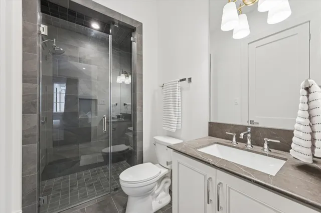 a bathroom with a granite countertop sink a toilet and shower