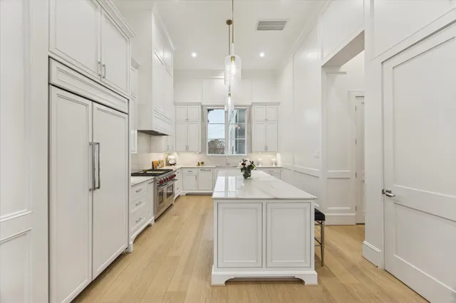 a large white kitchen with a sink stainless steel appliances and cabinets