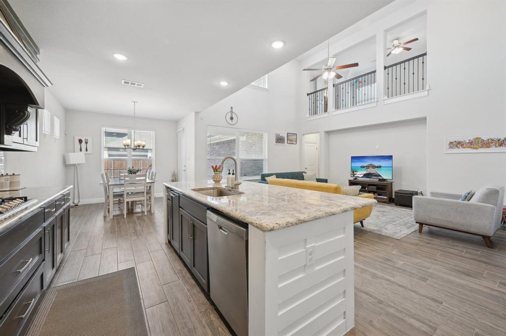 2172 Poppyvine Road Frisco, TX 75033 - Photo 39 of 40 Kitchen with light stone countertops, open floor plan, decorative light fixtures, wood tiled floors, and dishwasher