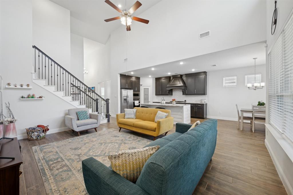 2172 Poppyvine Road Frisco, TX 75033 - Photo 10 of 40 Living room with dark wood-style floors, ceiling fan, a high ceiling, and a chandelier