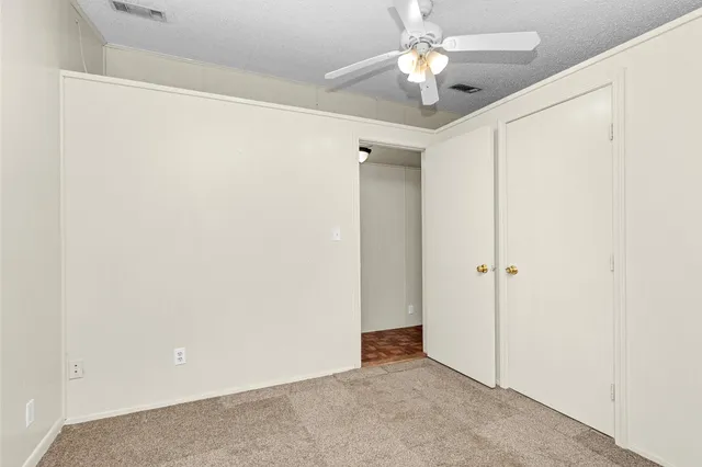 an empty room with closet and a chandelier fan
