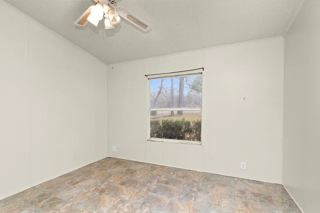 an empty room with a chandelier fan and windows