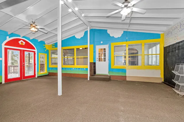 a view of an empty room with window ceiling fan