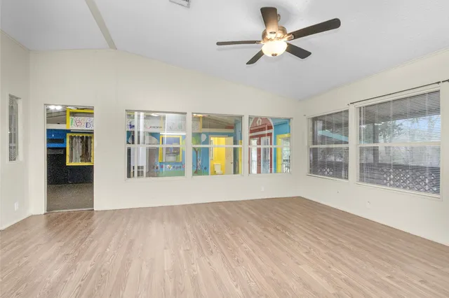 a view of an empty room with a window and wooden floor