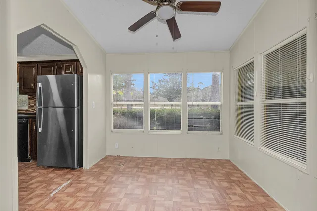 a view of an empty room with a window and kitchen view
