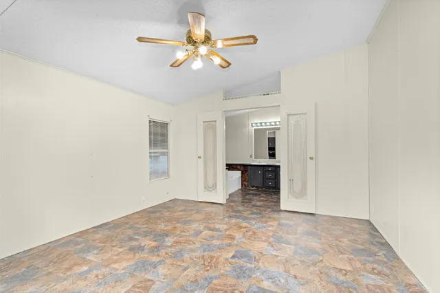 an empty room with chandelier fan and windows